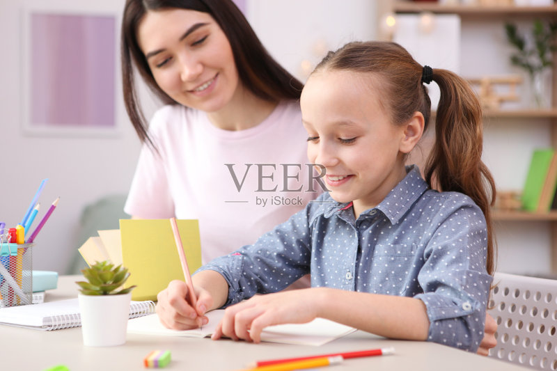 妈妈帮助女孩做家庭作业。孩子和父母。正版图片素材