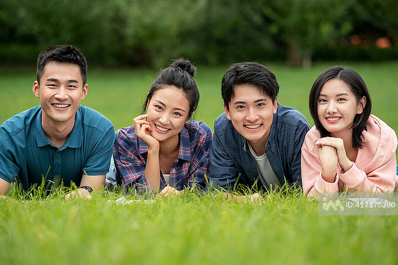 快乐的大学生趴在草地上照片摄影图片