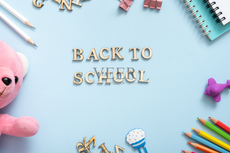 笔记本，笔记，钢笔，回形针，在柔和的蓝色背景。办公桌上有回学校的文本。平躺正版图片素材